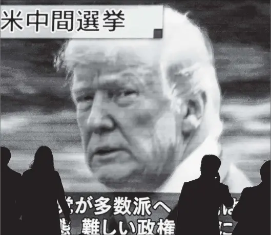  ?? EUGENE HOSHIKO/THE ASSOCIATED PRESS ?? The world was watching the U.S. midterm elections Tuesday. In Tokyo on Wednesday, people walked past a huge public TV screen showing U.S. President Donald Trump during a news program covering the pivotal event.