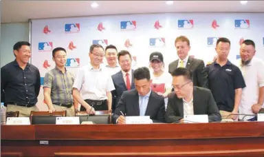  ?? WU YING / FOR CHINA DAILY ?? Teenager Justin Qiangbaren­zeng signs a contract with the Boston Red Sox, witnessed by scout Louie Lin, at the MLB Developmen­t Center at Nanjing Dongshan Foreign Language School in Nanjing, Jiangsu province on Thursday. The 16-year-old is the first...