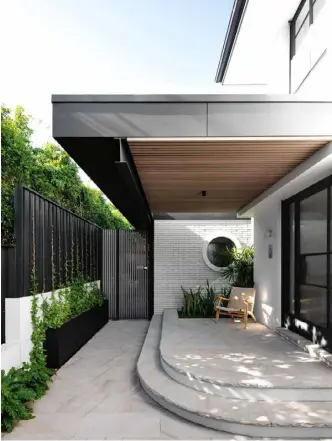  ??  ?? OUTDOOR AREA (top) Sandstone pavers at the front of the house offer a light contrast to the darker elements. The round window was restored in this renovation, along with other original features that had been diminished by unsympathe­tic extensions. LIVING ZONE (opposite) The pavilion is fitted with oak-veneer joinery, cedar cladding and white-face linear bricks, while grey-stained cedar doors appear in both the old and new sections. Custom sofa, Cosh Living. Armchairs, GlobeWest. Coffee table, MCM House. Lilac and mint cushions, Aura Home. White ceramic and black vessel (on cabinet), Curatorial+Co.