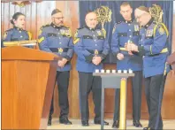  ?? DAVID JALA/CAPE BRETON POST ?? Chief Peter McIsaac, right, shelters a candle during a Holocaust memorial service at the Temple Sons of Israel Synagogue in Sydney on Sunday as Sgt. Erin Donovan, from left, Sgt. Barry Best, Staff-Sgt. Gilbert Boone, Deputy Chief Robert Walsh look on....