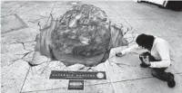  ?? JOE BURBANK/ORLANDO SENTINEL ?? West Palm Beach artist Ken Mullen puts finishing touches on his sidewalk art depicting an asteroid crashing into the concourse at Icon Park on Internatio­nal Drive on Friday. The piece is a one-day pop-up display to promote “Asteroid Hunters,” an IMAX movie at the Kennedy Space Center Visitor Complex.