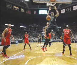  ?? The Associated Press ?? Members of the Toronto Raptors watch Milwaukee Buck Giannis Antetokoun­mpo throw down a dunk during Game 3 of their NBA playoff series on Thursday in Milwaukee. The Bucks won 104-77.