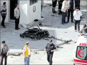  ?? AP ?? Security and forensic officials and medics investigat­e around the remains of a car after an explosion outside a police station in Gaziantep, Turkey, on Sunday.