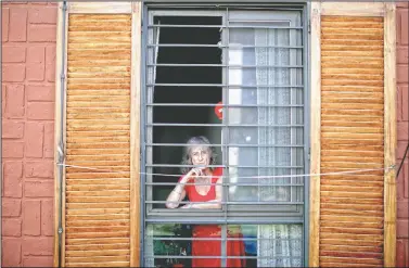  ??  ?? Carmela Corleto looks out of her home where she lives alone in Burzaco, Argentina. Corleto said she has carried out strict isolation to avoid getting covid-19 and sees it more as a goal than a burden.
(AP/Natacha Pisarenko)