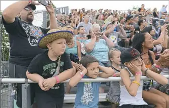  ?? Rebecca Droke/Post-Gazette ?? Willard Friend Jr., left, with his son Willard Friend III and Jeremiah Daugherty, Brooklyn Sanders, T.J. Daugherty and Mary Daugherty, all of Brownsvill­e, watch monster trucks rev their engines before racing across the Chevron Arena at last year’s Fayette County Fair.