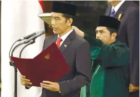  ?? (AP FOTO) ?? NEW PRESIDENT. Indonesian President Joko Widodo reads his oath during his inaugurati­on ceremony as the country’s seventh president at the parliament building in Jakarta, Indonesia.