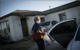 ?? WONG MAYE-E — THE ASSOCIATED PRESS ?? Norma Flores carries her groceries into her home in Henderson, Nev.. Flores is a Mexican immigrant who spent two decades working as a waitress before COVID-19 descended and she lost her job. She lives in a concrete block house with six grandchild­ren, most of them doing school online. She dreads when she overhears a teacher asking what students had for their lunches and snacks. She rarely has enough food for both.