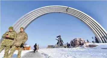  ??  ?? Ukrainian soldiers stand in front of huge Soviet-era arch in Kiev, symbolisin­g Ukraine and Russia’s friendship and union, where an unknown artist added a crack following recent tensions. — AFP