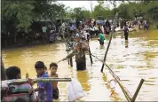  ?? BERNAT ARMANGUE — THE ASSOCIATED PRESS ?? Rohingya Muslims, who crossed over recently from Myanmar into Bangladesh, cross a flooded area to find alternate shelter after their camp was inundated with rainwater near Balukhali refugee camp on Tuesday.