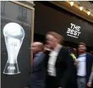  ?? (Reuters) ?? PEOPLE WALK past a FIFA logo in London.