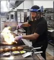  ?? MARCIO JOSE SANCHEZ - THE
ASSOCIATED PRESS ?? A cook prepares a meal at Slater’s 50⁄50 Wednesday, July 1, in Santa Clarita, Calif.