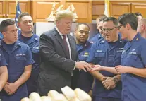  ?? SUSAN WALSH/ASSOCIATED PRESS ?? President Donald Trump is presented with a challenge coin as he meets with members of the U.S. Coast Guard stationed in Riviera Beach, Fla., on Thanksgivi­ng Day.