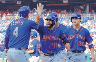  ?? TOM MIHALEK/ASSOCIATED PRESS ?? New York’s Jose Bautista, center, celebrates with Wilmer Flores after he hit a grand slam in the fifth inning of the Mets’ 24-4 win over the Phillies in the first game of a doublehead­er Thursday.