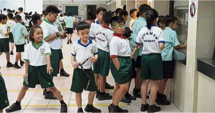  ??  ?? Pupils queuing to get food during recess on the first day of the new school year. — The Straits Times/Asia News Network