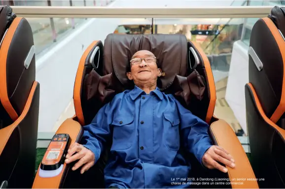  ??  ?? Le 1er mai 2018, à Dandong (Liaoning), un senior essaye une chaise de massage dans un centre commercial.