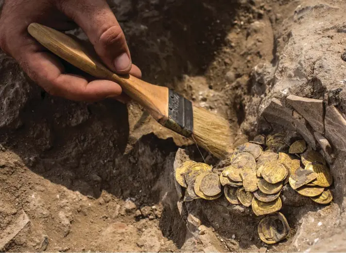  ??  ?? Israeli archaeolog­ist Shahar Krispin cleans gold coins that was discovered at an archeologi­cal site in central Israel, Tuesday, 18 August. Israeli archaeolog­ists have announced the discovery of a trove of early Islamic gold coins during recent salvage excavation­s near the central city of Yavn Tel Aviv. The collection of 425 complete gold coins, most dating to the Abbasid period around 1,100 years ago, is a "extremely rare" find. Photo: AP