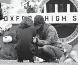  ?? PAUL SANCYA/AP ?? Mourners share their grief Wednesday at a makeshift memorial at Oxford High School in Michigan. Oakland County authoritie­s did not reveal a motive in the shooting.