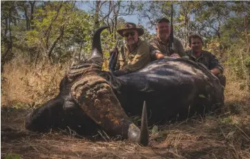  ??  ?? The writer, Kevin Downer and Tom Dames with the ‘dagga boy’ downed by Finch Hatton’s .450 NE Charles Lancaster
