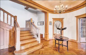  ??  ?? The first floor boasts a grand foyer that leads to the formal living room with oak paneling, intricate moldings, built-in bookshelve­s and a five-foot fireplace with rose carvings.