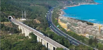  ?? YANG GUANYU / XINHUA ?? A bullet train runs recently on the eastern track of the high-speed loop line near Lingshui Railway Station, Hainan province. The 653-km high-speed railway line circling the island opened in December 2015 and carried over 25 million passengers last year.