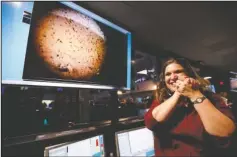  ?? The Associated Press ?? INSIGHT LANDS: An engineer smiles next to an image of Mars sent from the InSight lander shortly after it landed on Mars in the mission support area of the space flight operation facility at NASA’s Jet Propulsion Laboratory Monday, in Pasadena, Calif.