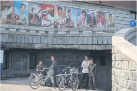  ??  ?? WHAT’S ON?: Men stand next to bicycles beneath film posters at the 15th Pyongyang Film Festival in the capital of North Korea.