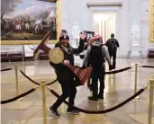  ?? WIN MCNAMEE Getty Images ?? Adam Christian Johnson carries the lectern bearing the seal of the Speaker of the House during Wednesday’s riot at the U.S. Capitol Building.