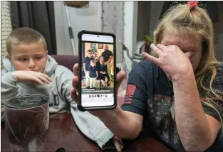  ?? MAX BECHERER — THE TIMES-PICAYUNE — THE NEW ORLEANS ADVOCATE VIA AP ?? Darra Ann Morales, right, shows a photo of her son Chaz Morales and his family on her phone, as Chaz Jr., 10, comforts his grandmothe­r at their home in Slidell, La., Wednesday, April 14, 2021. Darra Ann Morales is the mother and Chaz Jr. is the son of Chaz Morales, who is one of the crew members missing from the capsized vessel Seacor Power that departed from Port Fourchon when severe weather struck Tuesday.