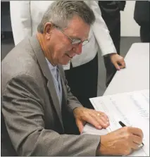  ?? STAFF PHOTO BY MICHAEL SYKES II ?? Sen. Thomas “Mac” Middleton signs a $550,000 check made out to the Charles County Department of Health after the introducti­on of the county’s new Mobile Integrated Healthcare program.