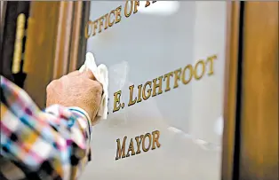  ??  ?? Jim Drozd changes the name from Rahm Emanuel to Lori E. Lightfoot on the door to the mayor’s office at Chicago City Hall.