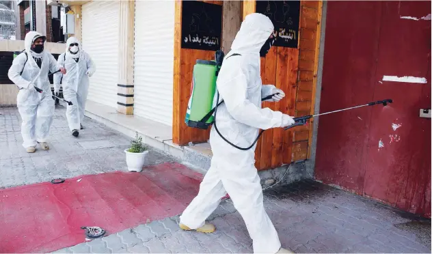  ?? Agence France-presse ?? ↑
Iraqi health officials disinfect a street in Baghdad’s Zayoun area on Wednesday.