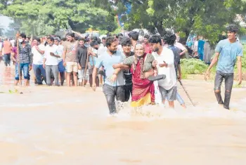  ?? AP ?? People wade through a flooded street Saturday in Nellore, India. At least 17 people have died and dozens are reported missing in the southern Indian state of Andra Pradesh after days of heavy rains, authoritie­s said Saturday. The state has been hit by intense downpours since Thursday, sparking massive floods in at least five areas.