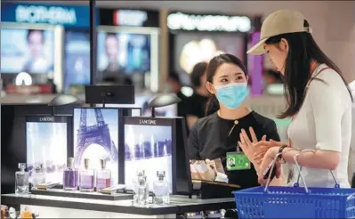  ?? MENG ZHONGDE / FOR CHINA DAILY ?? A tourist shops at a duty-free store in Hainan province.