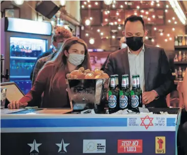  ??  ?? Israel motiviert die eigene Bevölkerun­g, möglichst zahlreich an den Impfungen teilzunehm­en. In einer Bar in Tel Aviv erha