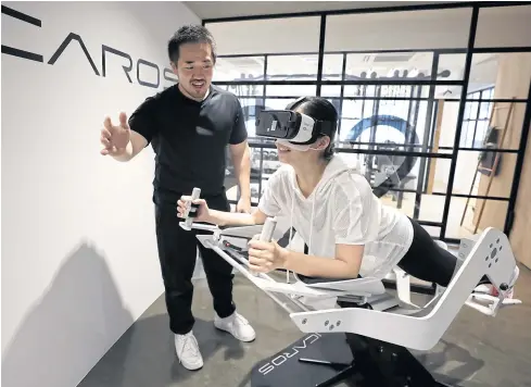  ??  ?? Shuhei Miyajima, a personal trainer, left, explains the use of the Icaros VR fitness machine, manufactur­ed by Icaros GmbH, at The Body Ride personal training gym in Tokyo.