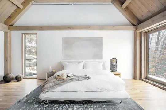  ?? PHOTO BY DREW HADLEY, COURTESY OF CATLIN STOTHERS DESIGN ?? Wood beams and wood flooring adds some warm tones to balance out the white walls and minimalist decor. Textiles, like the bedding and the area rug, also make the room look less austere and more inviting.