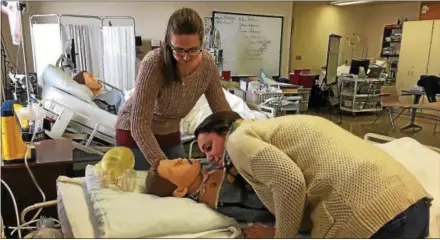  ?? LESLIE KROWCHENKO — DIGITAL FIRST MEDIA ?? Delaware County Community College nursing students Melissa Robinson, checking pulse, and Allison Keeports, listening for breath sounds, used a training mannequin to demonstrat­e the CPR performed on fellow student Rich Zerbey.