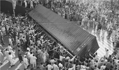  ?? K. M. CHAUDARY/ THE ASSOCIATED PRESS ?? Pakistani protesters topple a shipping container police used to block the road to the U.S. consulate in Lahore, Pakistan on Friday.
