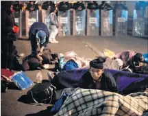  ?? AP PHOTO ?? A migrant get ready to spend the night in front of a line of Mexican police in riot gear at the Chaparral border crossing in Tijuana, Mexico, Thursday.