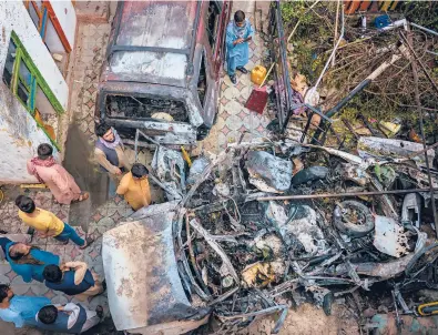  ?? MARCUS YAM/LOS ANGELES TIMES ?? Relatives and neighbors of a family gather around an incinerate­d vehicle in Kabul after a U.S. drone strike.