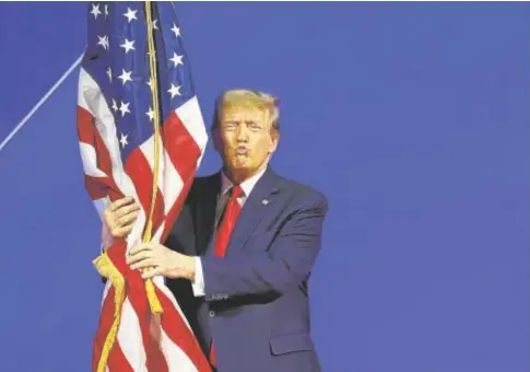  ?? // AFP ?? Trump abraza una bandera estadounid­ense en la Conferenci­a Política de Acción Conservado­ra, en Washington