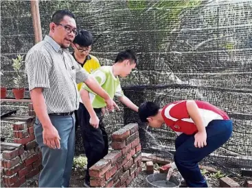  ??  ?? Special needs teacher Dr Muhamad Khairul teaching his students to be self-sufficient.