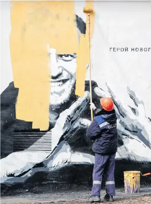  ?? REUTERS ?? A worker paints over graffiti depicting jailed Russian opposition politician Alexei Navalny in Saint Petersburg, Russia on April 28. The graffiti reads: “The hero of the new age.”