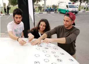  ?? Photo by M. Sajjad ?? Students put their pledge stickers on a vehicle as a part of the Drive Safely campaign at American University Sharjah. —