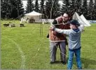  ??  ?? Pascal Nienhaber aus dem Ruhrgebiet zeigt dem Jungen Paul beim Kinderfest, wie mit dem Bogen geschossen wird.