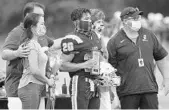  ?? STEPHEN M. DOWELL/ORLANDO SENTINEL ?? Foundation Academy player Travis Hutchinson (20) enjoys Senior Day honors with his family and head coach Brad Lord, right, in Winter Garden on Sept. 4.