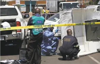  ?? Associated Press 2014 ?? A forensics team searches for clues at the scene of a cash transit heist in 2014 in Johannesbu­rg. Criminal syndicates are blamed for a sharp increase in the attacks this year.