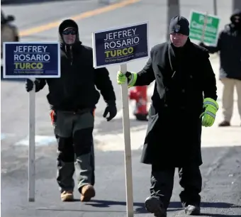  ?? NANCY LANE / HERALD STAFF ?? TOPS: Carl Johnson and David Anderson hold campaign signs for Jeffrey Turco outside a Winthrop polling place Tuesday. Turco claimed victory in the four-way race with 36.2% of the vote.