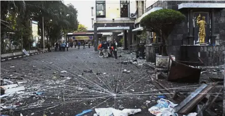  ?? — AP ?? Probe in progress: Strings of thread placed by police officers to determine the trajectory of the explosion outside one of the targeted churches in Surabaya.