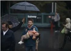  ?? ANDRES KUDACKI — THE ASSOCIATED PRESS ?? A guardian carries a child as his partner holds the umbrellas following heavy rains on Friday, Sept. 29, 2023.